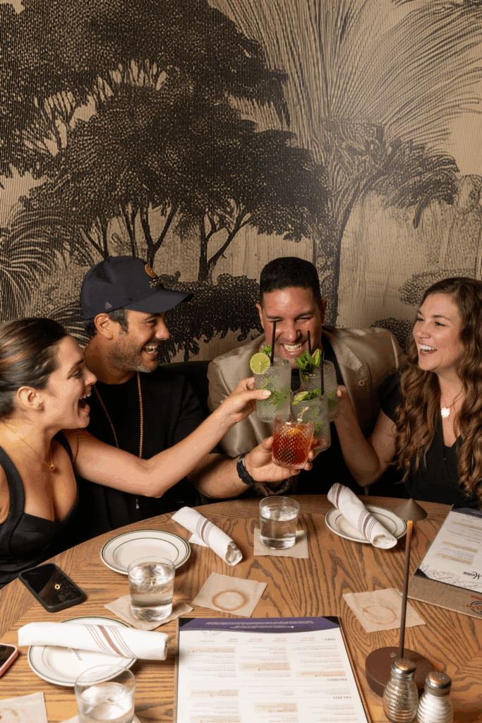 Group of friends toasting with Cuban mojitos at Havana 1957, enjoying a fun and lively dinner experience in Miami Beach